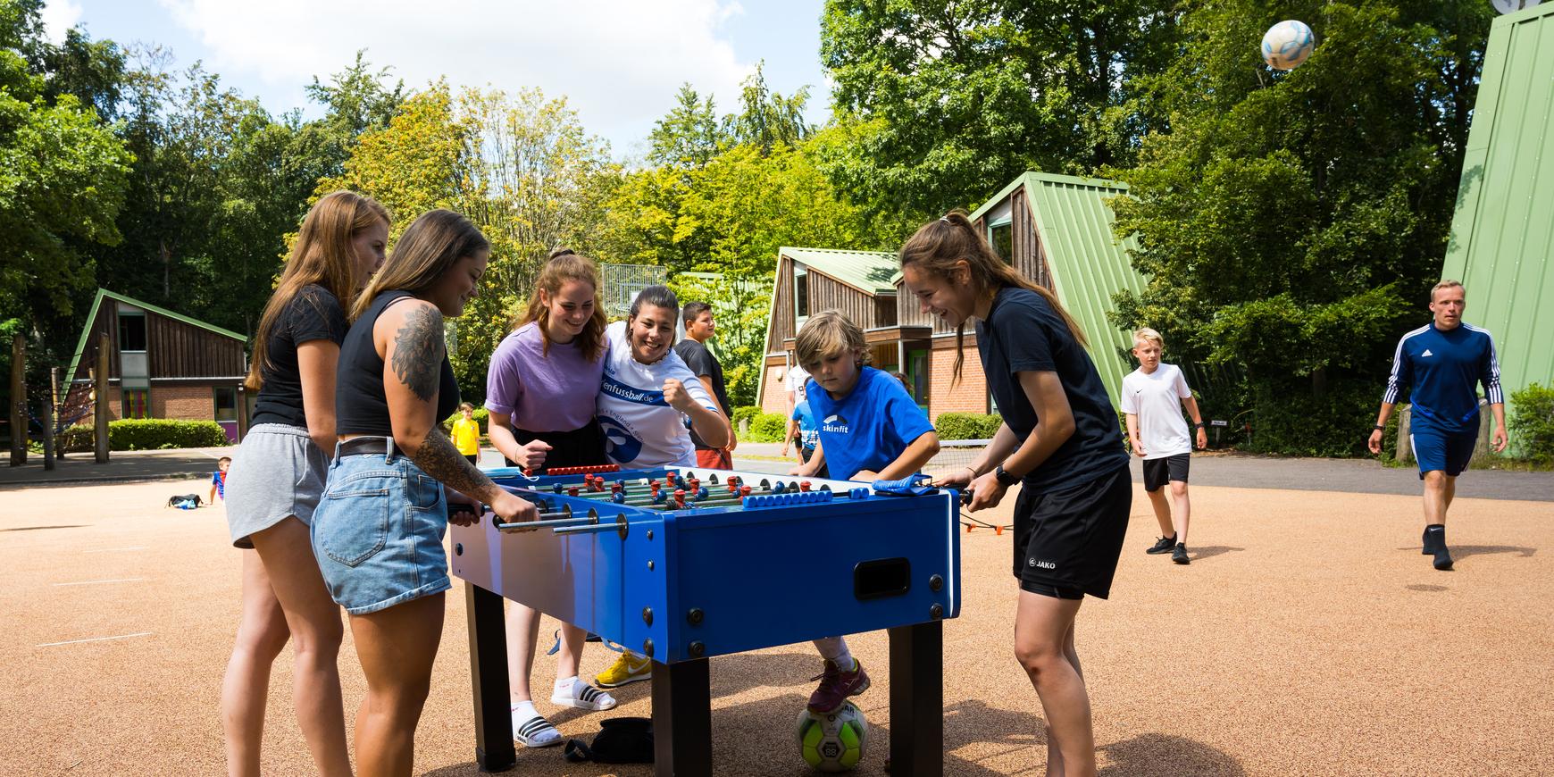 Jugendliche spielen draußen am Kicker-Automat