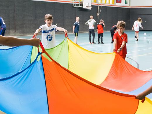 Kinder spielen mit Tuch in Sporthalle